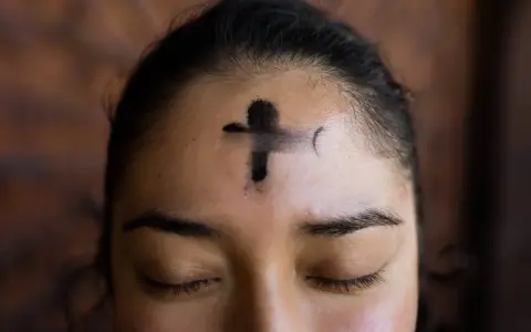 A cross of ashes marks a forehead, a solemn reminder of scripture for Ash Wednesday.