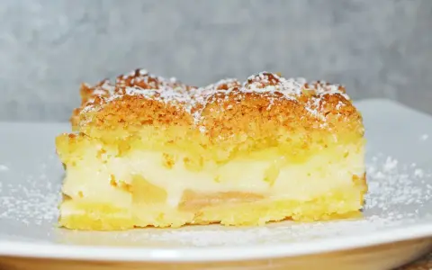 Pyszne ciasto z jabłkami i budyniem, posypane cukrem pudrem. Idealne na deser.