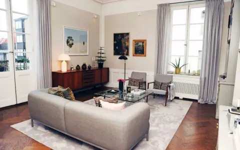 Ett modernt vardagsrum med en grå soffa, glasbord och konst. Johan Pråmell skulle trivas här.