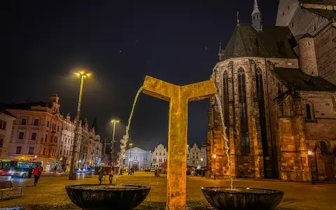 Złota fontanna w centrum miasta, obok zabytkowego kościoła. Wieczorne Pilzno, pełne urokliwych atrakcji.