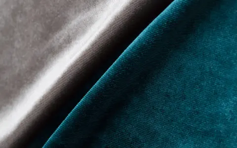 Tessuto in velluto a coste blu petrolio e grigio tortora, che mostra la morbidezza e la lucentezza di questo acetato che tessuto è.