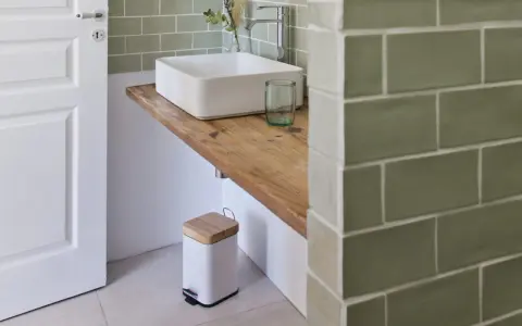Plan de travail pour salle de bain avec lavabo carré, robinetterie moderne et poubelle design.