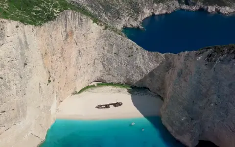Navagio, jedna z najpiękniejszych plaż Zakynthos, z wrakiem statku na białym piasku i turkusową wodą.