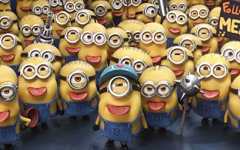 Grupa wesołych, żółtych minionków postacie w niebieskich ogrodniczkach, jeden z nich trzyma tabliczkę "Follow MEL".