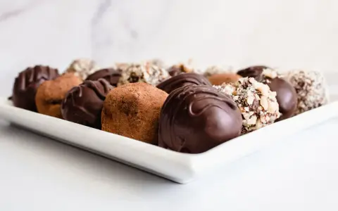 Variedad de trufas de chocolate, algunas cubiertas de cacao y otras con frutos secos picados. ¡Perfectas para aprender como hacer trufas de chocolate!