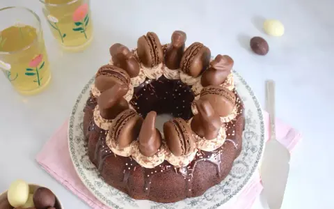 Gâteau rond au chocolat, décoré de macarons, de lapins en chocolat et d'une ganache carambar onctueuse.
