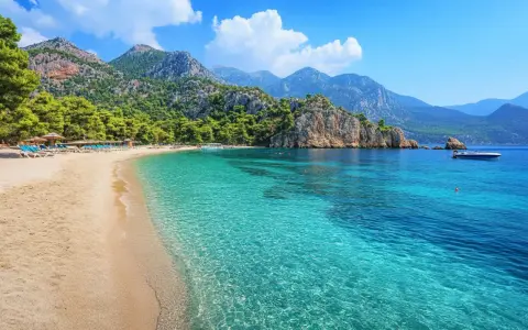 Piękna plaża w Turcji z turkusową wodą, górami i sosnami. Idealne miejsce na relaks.