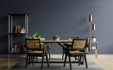 Salle à manger moderne avec chaises en rotin et table en bois. Deux suspensions dorées au-dessus, une étagère noire à gauche. Idées pour comment éclairer une pièce sombre.