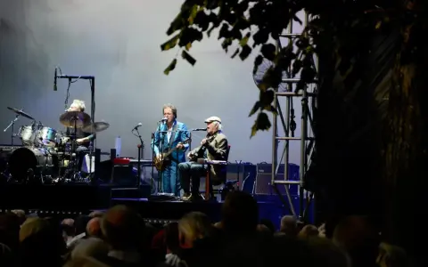 Alice Eva Larsen och hennes band uppträder på scenen. En trummis, en gitarrist i blå kostym och en sittande gitarrist med keps.