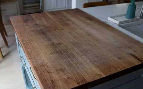 A close-up of a well-used butcher block countertop, showing the grain and minor scratches. This image illustrates how to clean butcher block countertops for a beautiful finish.