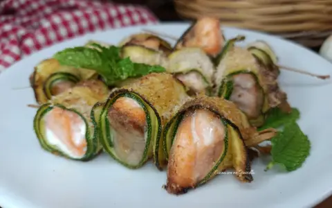Deliziosi involtini di zucchine con salmone e formaggio, guarniti con menta fresca.