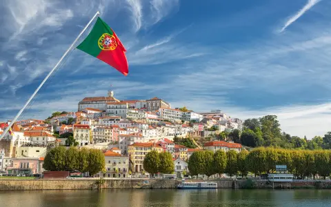 Wspaniała portugalia pogoda w grudniu. Flaga Portugalii powiewa nad malowniczym miastem na wzgórzu, z rzeką w tle.