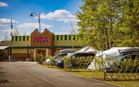 Zator Energylandia trasa: parking z samochodami i namiotami pod budynkiem "American Dream" w słoneczny dzień.
