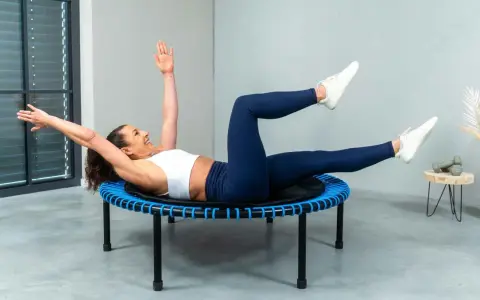 Frau macht ein intensives Workout auf einem Trampolin. Sie trainiert ihren Bauch, eine Übung, die man auch bei Tabata machen kann.