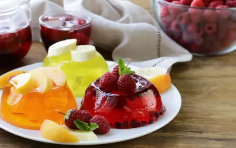 Tre colorate gelatine per dolci, guarnite con frutta fresca, invitano a un assaggio rinfrescante.