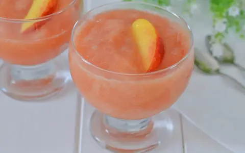 Coppa di granita alla pesca, rinfrescante e dolce, guarnita con una fetta di pesca fresca. Perfetta per un'estate golosa.