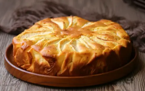 Una deliziosa torta di mele dorata, con le mele disposte a raggiera sulla superficie, pronta per essere gustata.