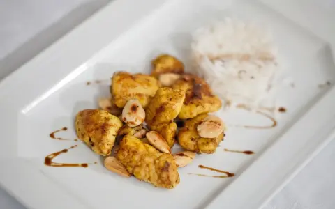 Piatto di cous cous con pollo al curry, mandorle e riso bianco.