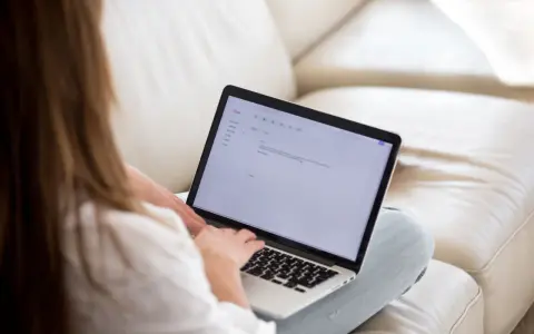 Kobieta pisze maila na laptopie, podkreślając ważne fragmenty tekstu.