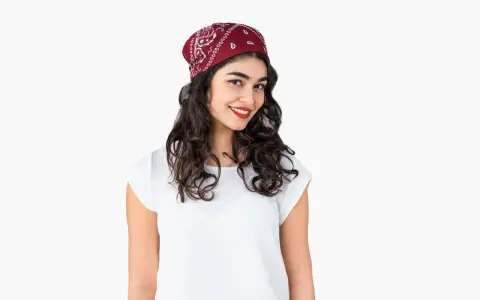 Uśmiechnięta dziewczyna z burzą loków, na głowie ma czerwoną bandana. Pokazujemy, jak zawiązać chustę na głowie.