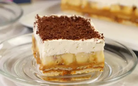 Przepis na Banoffee Pie: warstwy ciastek, karmelu, bananów i bitej śmietany, posypane czekoladą.