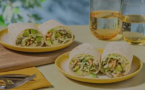 Leckeres Tortilla-Rezept mit Avocado und Garnelen, serviert auf gelben Tellern mit Gläsern mit Getränken.