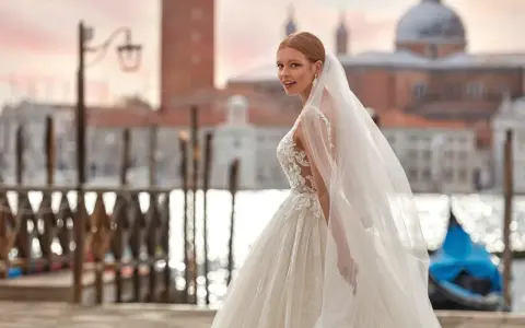 Sposa con abito da sogno e velo svolazzante a Venezia, con gondola blu sullo sfondo. Perfetta per un matrimonio da favola, anche con stivali sposa.