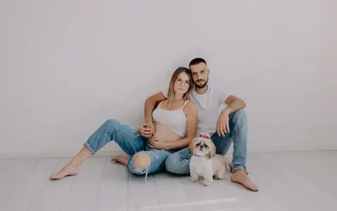 Ciąża w obiektywie laura kania fotografia: przyszli rodzice z pieskiem siedzą na podłodze.