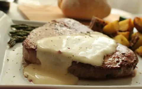 Jugosa ternera en salsa cremosa, acompañada de espárragos y patatas asadas. Un plato principal delicioso.