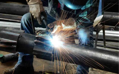 Un saldatore crea un legame forte, il vero significato del welding. Scintille luminose illuminano il metallo.