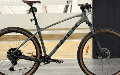 Szary rower górski Trek Marlin 6 z brązowymi oponami Maxxis, gotowy na przygodę.
