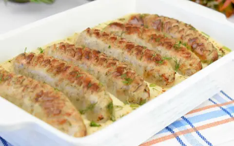 Aromaticzna biała kiełbasa w sosie chrzanowo-musztardowym, udekorowana świeżym koperkiem, podana w białej zapiekance.