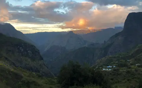 Al tramonto, le montagne della "diagonale des fous" si tingono di rosa. Un villaggio si intravede tra le valli verdi.