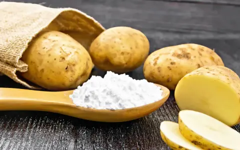 Kartoffeln und ein Löffel voller Kartoffelstärke, eine vielseitige kartoffelmehl alternative für Küche und Haushalt.