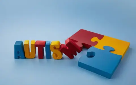 Kolorowe litery układają się w napis "AUTISM", obok fragmenty puzzli. Szukamy leków na autyzm dla dzieci, by pomóc im w rozwoju.