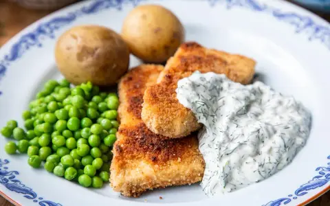 Panerad fisk med kokt potatis, gröna ärtor och en krämig skolans dillsås.