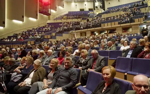 Widownia sali koncertowej, ludzie w eleganckich strojach, inspiracja: jak ubrać się na koncert muzyki filmowej.
