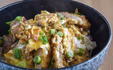 Oishi! Ein dampfendes Schüsselchen mit Reis, bedeckt mit knusprigem Hähnchen, Ei und Frühlingszwiebeln – ein Klassiker der japanischen Rezepte.