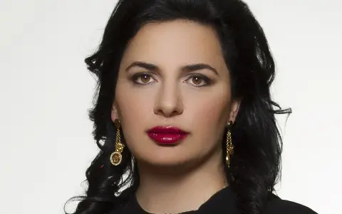 Portret Ruja Ignatova, kobiety o ciemnych włosach i wyrazistych ustach, w złotych kolczykach.