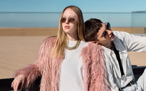 Chica con abrigo rosa peludo y collar dorado, apoyada en un chico con camisa blanca. Inspiración para como ser una chica aesthetic.