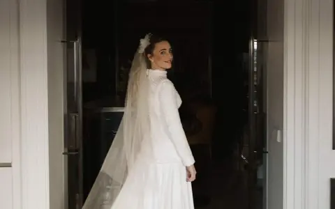 Novia sonriente con velo y vestido blanco, parte de un ajuar de novia tradicional, lista para su gran día.