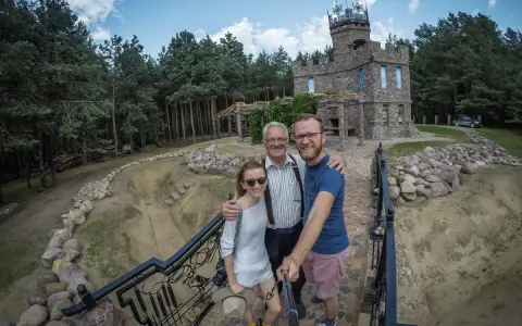 Rodzina pozuje do zdjęcia na tle kamiennego zamku, jednego z romantycznych miejsc na Podlasiu.