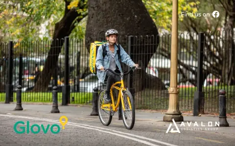 Kurier Glovo na rowerze z żółtą torbą. Dowiedz się, glovo co to jest - szybka dostawa jedzenia i nie tylko!