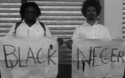 Dwóch mężczyzn trzyma transparenty z napisem "BLACK NEGER". Czy to wyraz buntu, czy prowokacja kwestionująca poprawność polityczną?