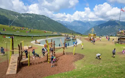 Un parco giochi in montagna con un laghetto, un galeone e tante famiglie che si divertono. Perfetto per le vacanze in montagna con bambini.