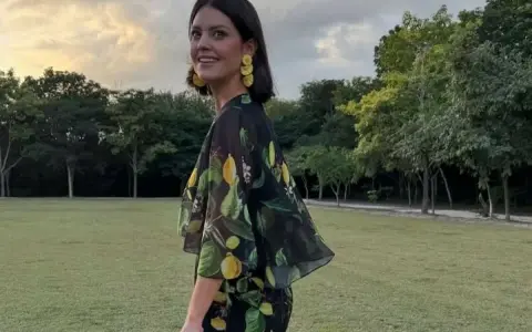 Isabelle Junot sonríe con un vestido estampado de limones, luciendo pendientes amarillos y un sombrero de paja en un día soleado.