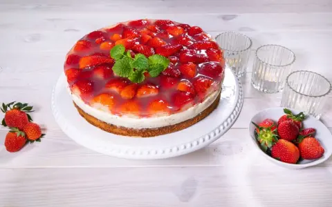 Eine köstliche Erdbeer Joghurt Sahne Torte, bedeckt mit frischen Erdbeeren und Tortenguss, garniert mit Minze.