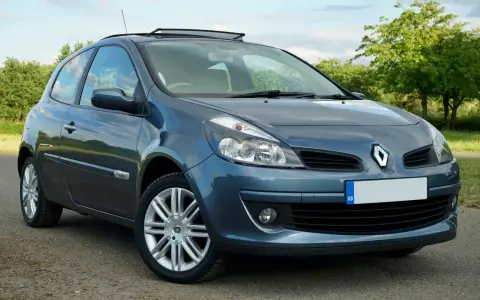 Renault Clio 3 bleue, vue de face, garée sur un chemin de terre.