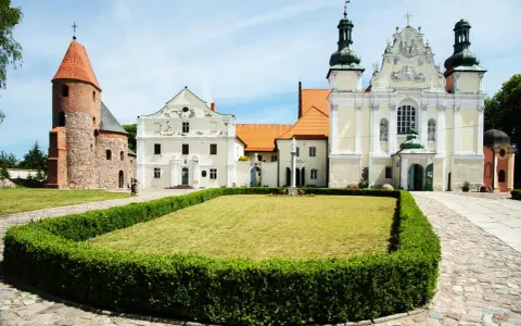 Kamienne kolumny w strzelnie otaczają trawnik przed barokowym kościołem i romańską wieżą.