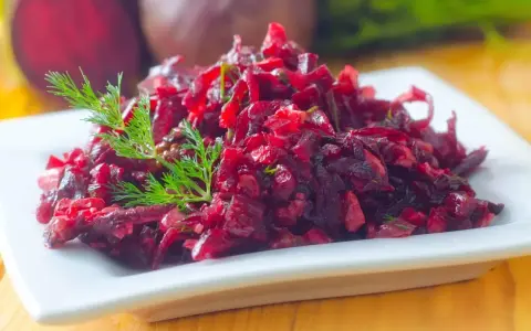 Prosta sałatka z buraków gotowanych, doprawiona koperkiem, podana na białym talerzu.